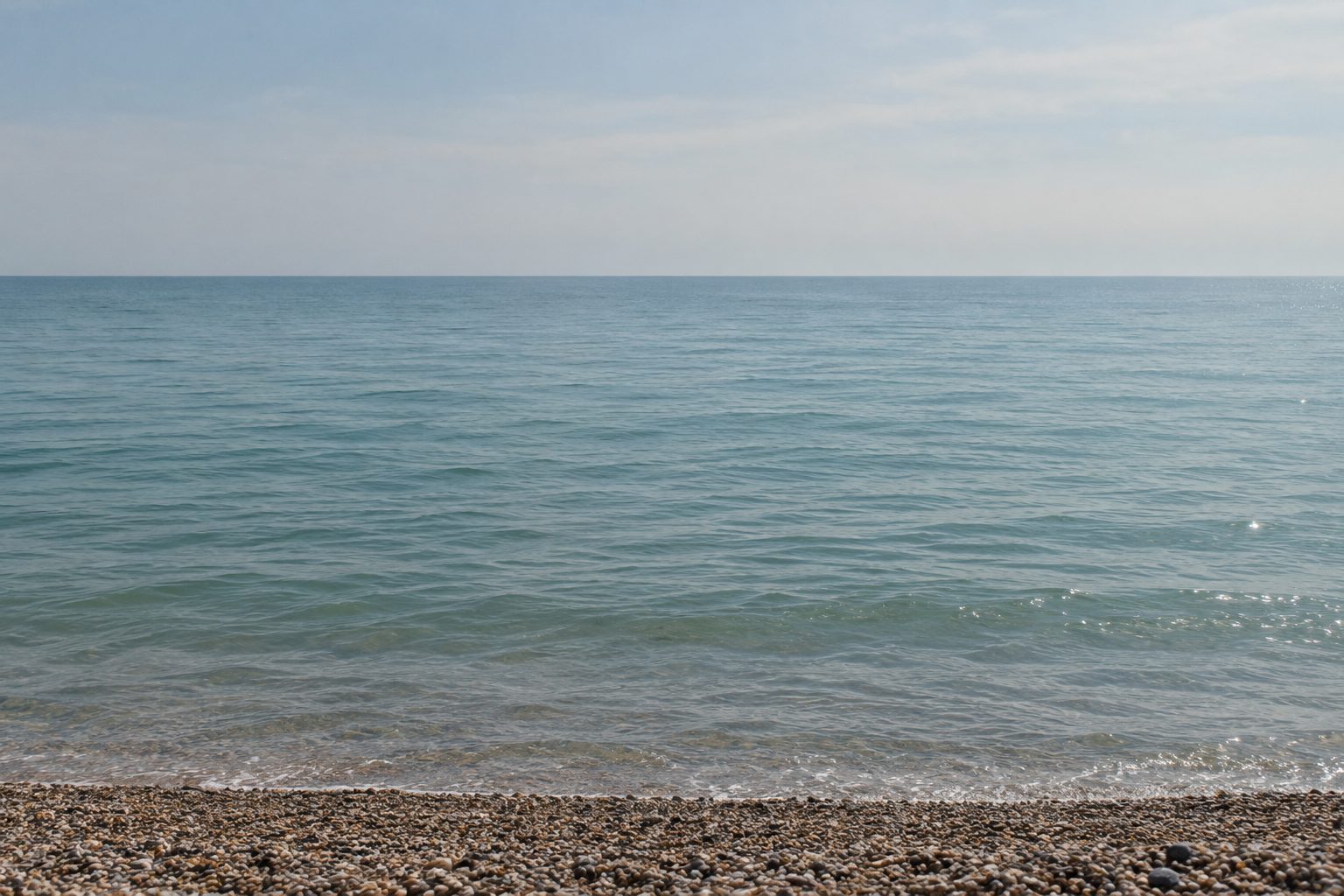 A calm sea seen from a shingle beach